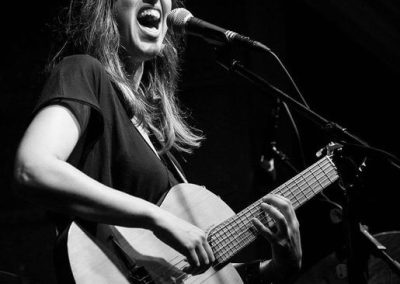 Susana Raya, Andalusian jazz singer songwriter and guitar player, passionately singing and playing guitar during a performance