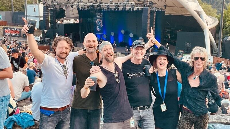 Progressive Rock band Inhalo band members celebrating at Night of the Prog Festival in Loreley, Germany, with the stage and festival crowd in the background.