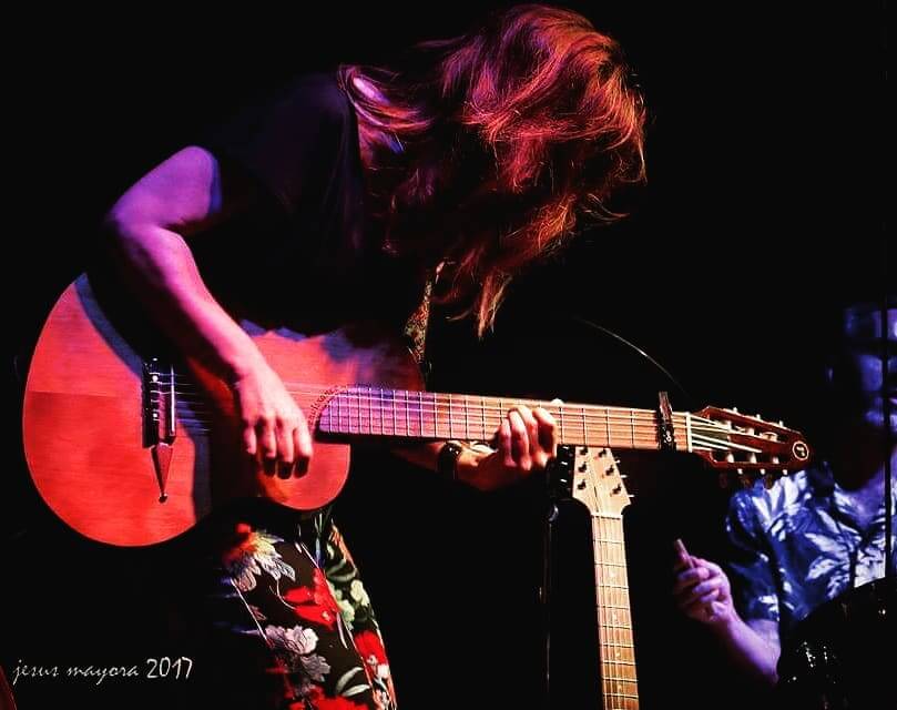 Susana Raya performing on stage with her RN-6 Renaissance guitar, deeply engaged in her music under moody lighting.